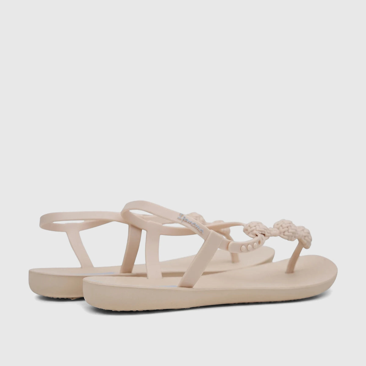 Pair of beige Ipanema Class Posh thong sandals with braided straps and blue logo, photographed from a low angle.