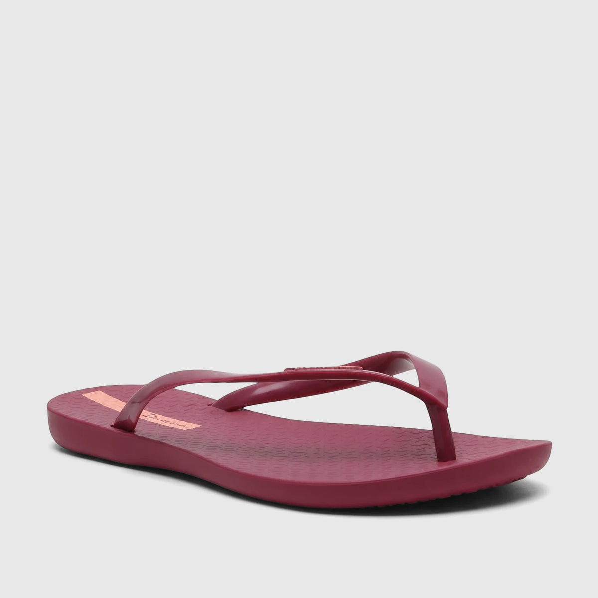 Ipanema Wave Fem burgundy patent flip-flop, viewed from a side angle, showcasing the textured sole and branded strap.