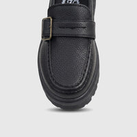 Close-up of a Klevas Boys black chunky sole loafer with a monk strap, brass buckle, pebbled faux leather, and a thick lug