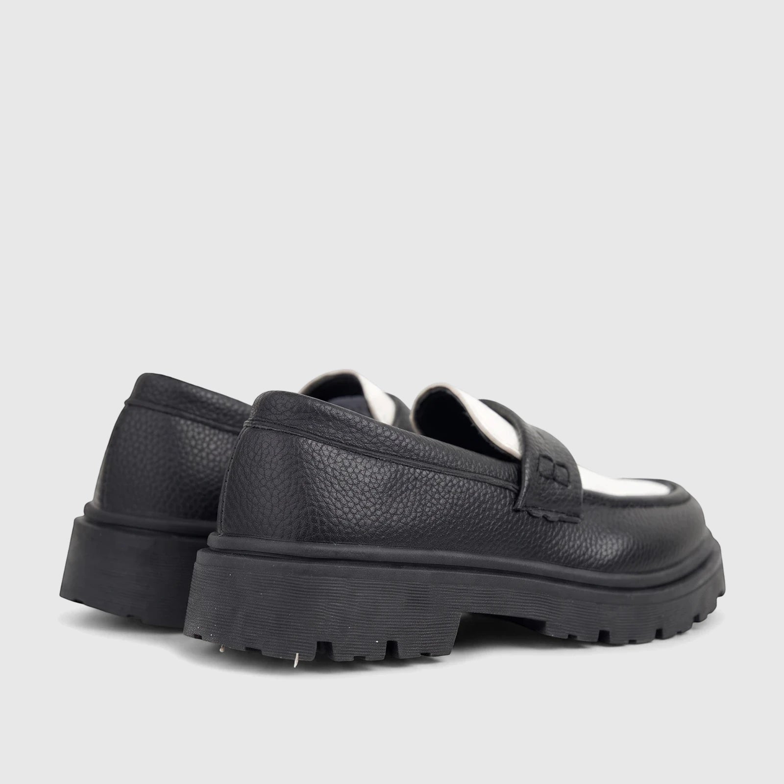 Pair of Klevas Boys chunky sole loafers in black and white, viewed from the back-side, showcasing their textured leather and