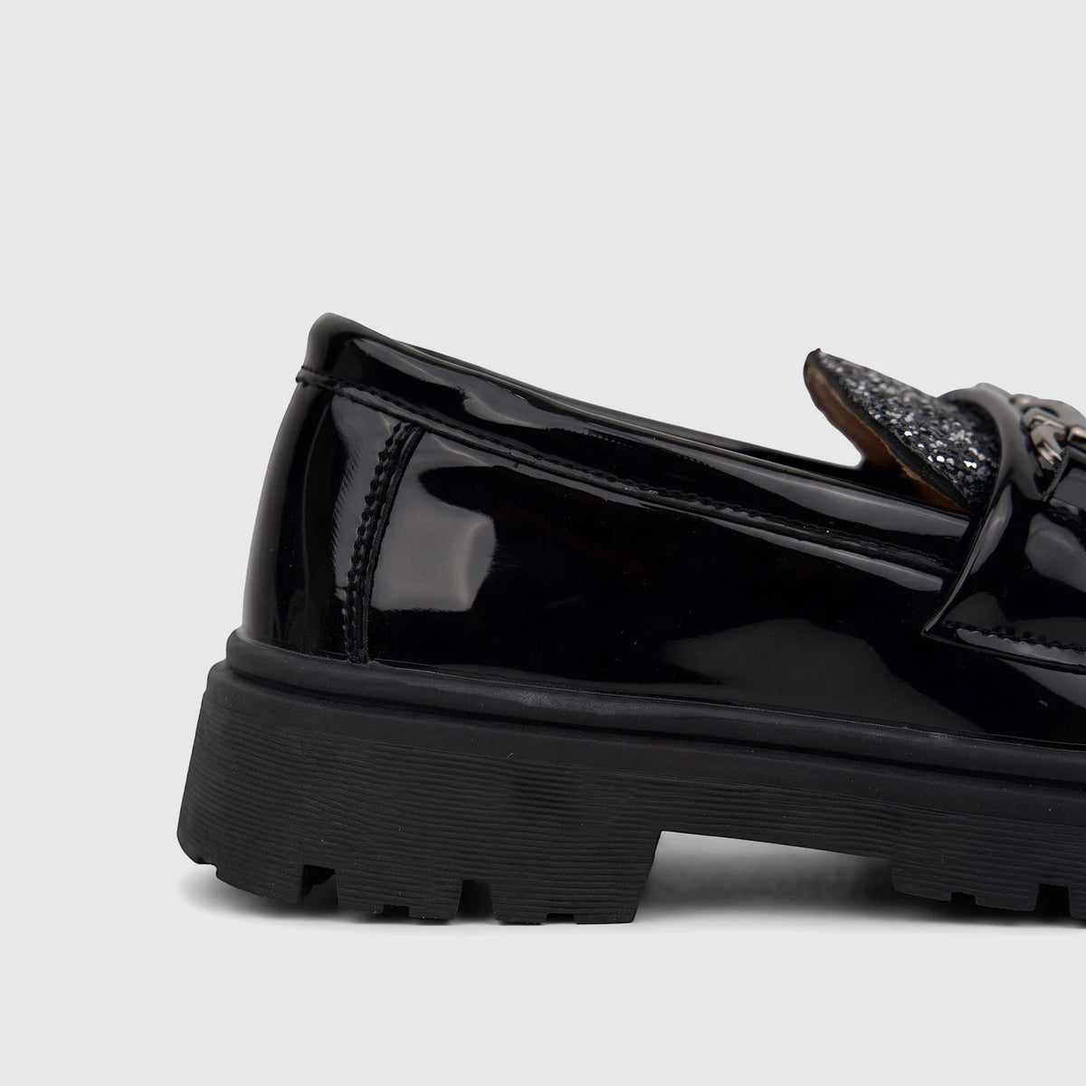 Close-up of a black patent leather Klevas Boys chunky sole loafer, showing the heel and side with a glitter accent and chain