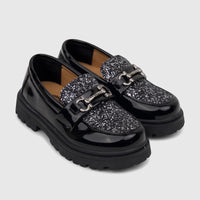 A pair of Klevas Boys Chunky Sole Loafers in black patent with a glitter vamp and silver chain hardware, showcased on a