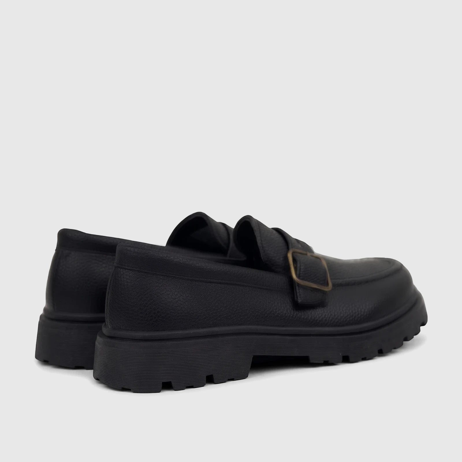 Pair of Klevas Boys Youth chunky sole loafers in black, featuring a pebbled texture and a brass monk strap buckle. Side-back