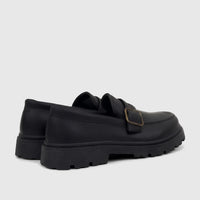 Pair of Klevas Boys Youth chunky sole loafers in black, featuring a pebbled texture and a brass monk strap buckle. Side-back