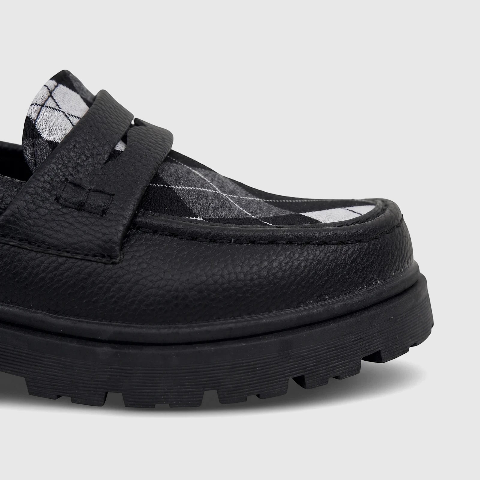 Close-up of a black Klevas Boys Youth chunky sole loafer with a black and white argyle pattern on the vamp, viewed from the