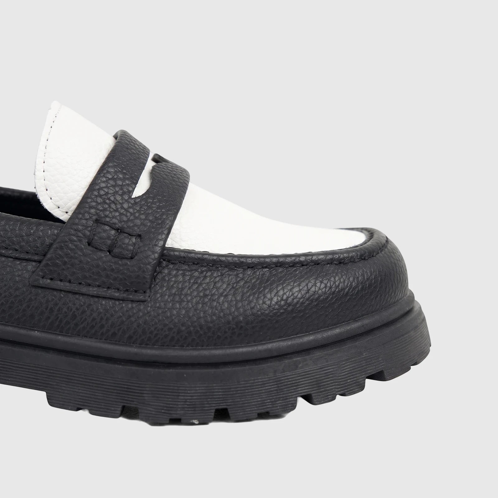 Close-up of a Klevas Boys Youth chunky sole loafer in black and white faux leather, showcasing the textured upper and lugged