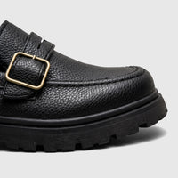 Black chunky sole monk strap loafer for boys youth sizes, featuring a textured finish and a brass buckle detail.
