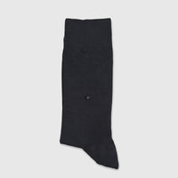 A single black men's micro modal sock, featuring a small diamond-shaped hole, displayed flat on a white surface.