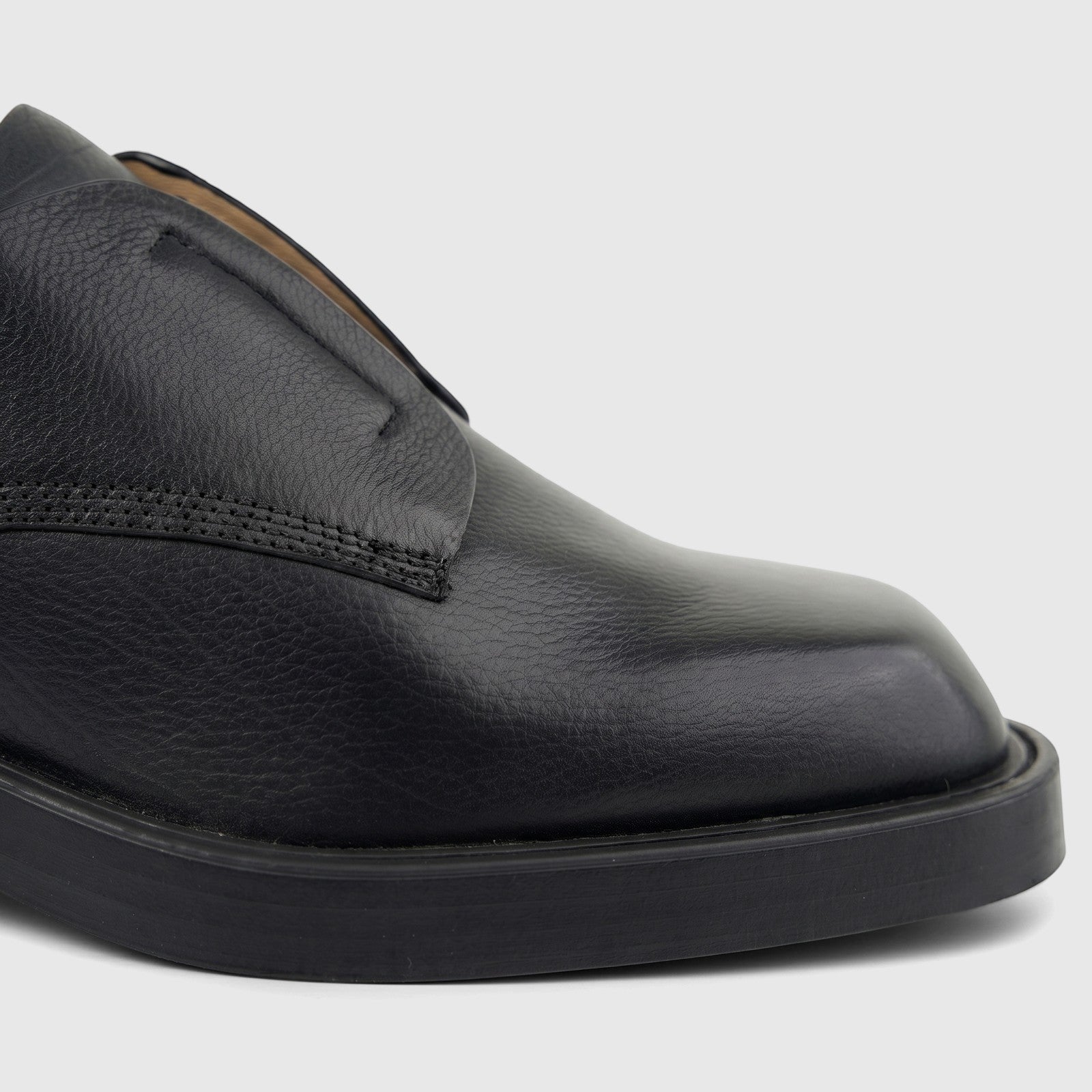 Close-up of a black grained leather lace-up shoe with a thick sole for ladies, seen from the side view.