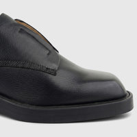 Close-up of a black grained leather lace-up shoe with a thick sole for ladies, seen from the side view.