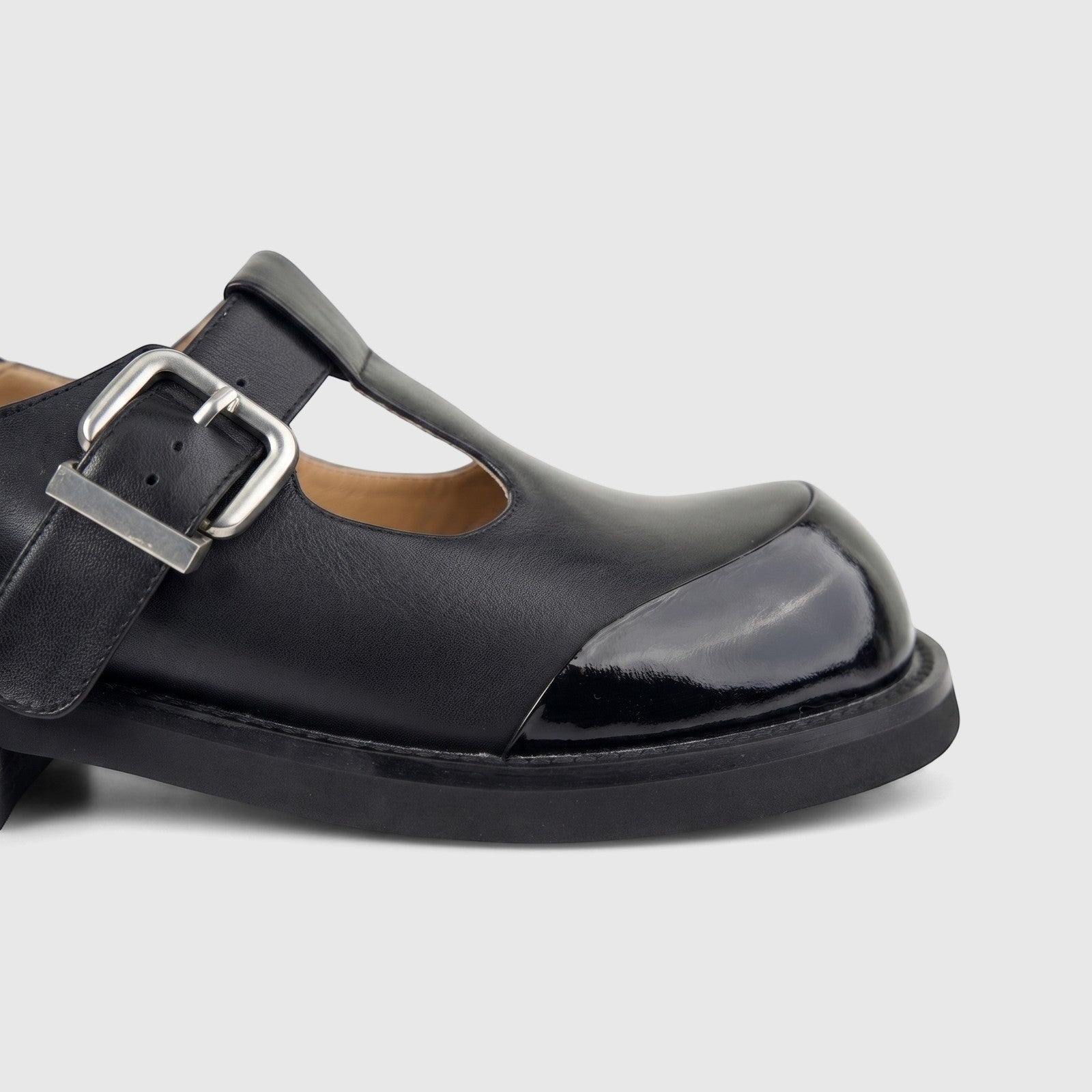 Close-up view of a Morbido Ladies Black Leather T-Bar Chunky Sole shoe with a silver buckle and glossy toe cap.