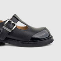 Close-up view of a Morbido Ladies Black Leather T-Bar Chunky Sole shoe with a silver buckle and glossy toe cap.