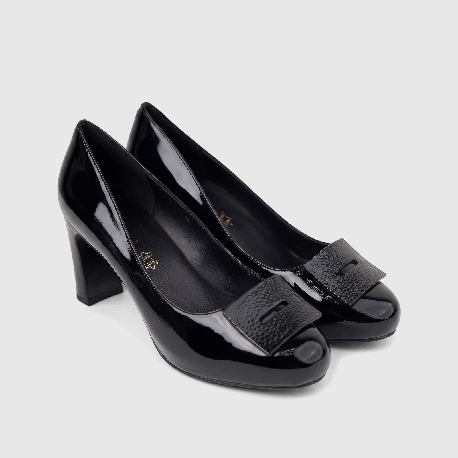 A pair of black patent leather Morbido ladies dress court shoes with block heels and square textured buckles, displayed on a