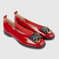 A pair of shiny dark red patent leather Morbido Ladies Leather Pump flat shoes, showcasing black bow details with gold-tone