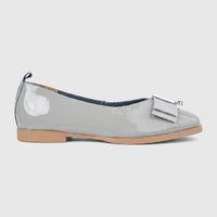 Side view of a Morbido Ladies Leather Pump in light grey patent leather with a decorative bow and silver buckle.