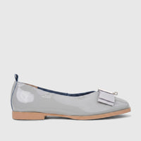 Light grey patent leather ladies' pump with a decorative bow, tan sole, and blue trim, viewed from the side.