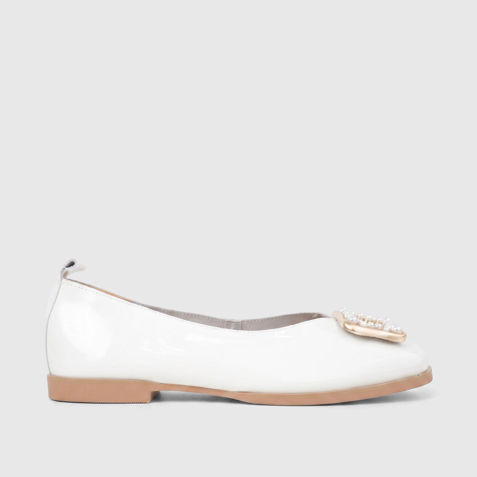 White patent leather ladies' flat shoe with a pearl and gold embellishment, featuring a tan sole, side view.