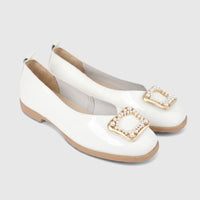 Pair of Morbido Ladies white patent leather pumps with gold-tone square buckles embellished with pearls, angled view.