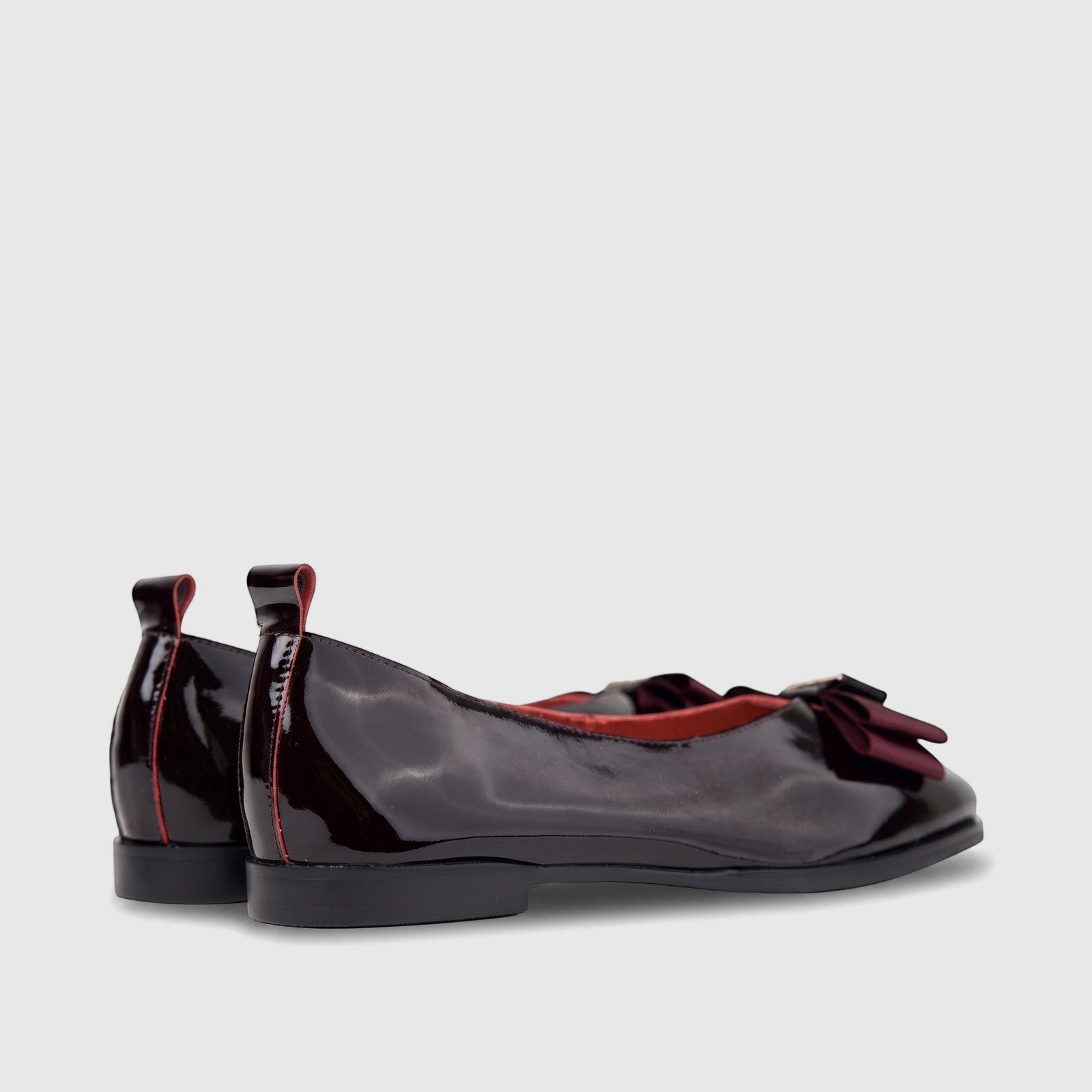 Pair of Morbido Ladies Wine Red patent leather ballet flats with a velvet bow, shown from the side and back view.