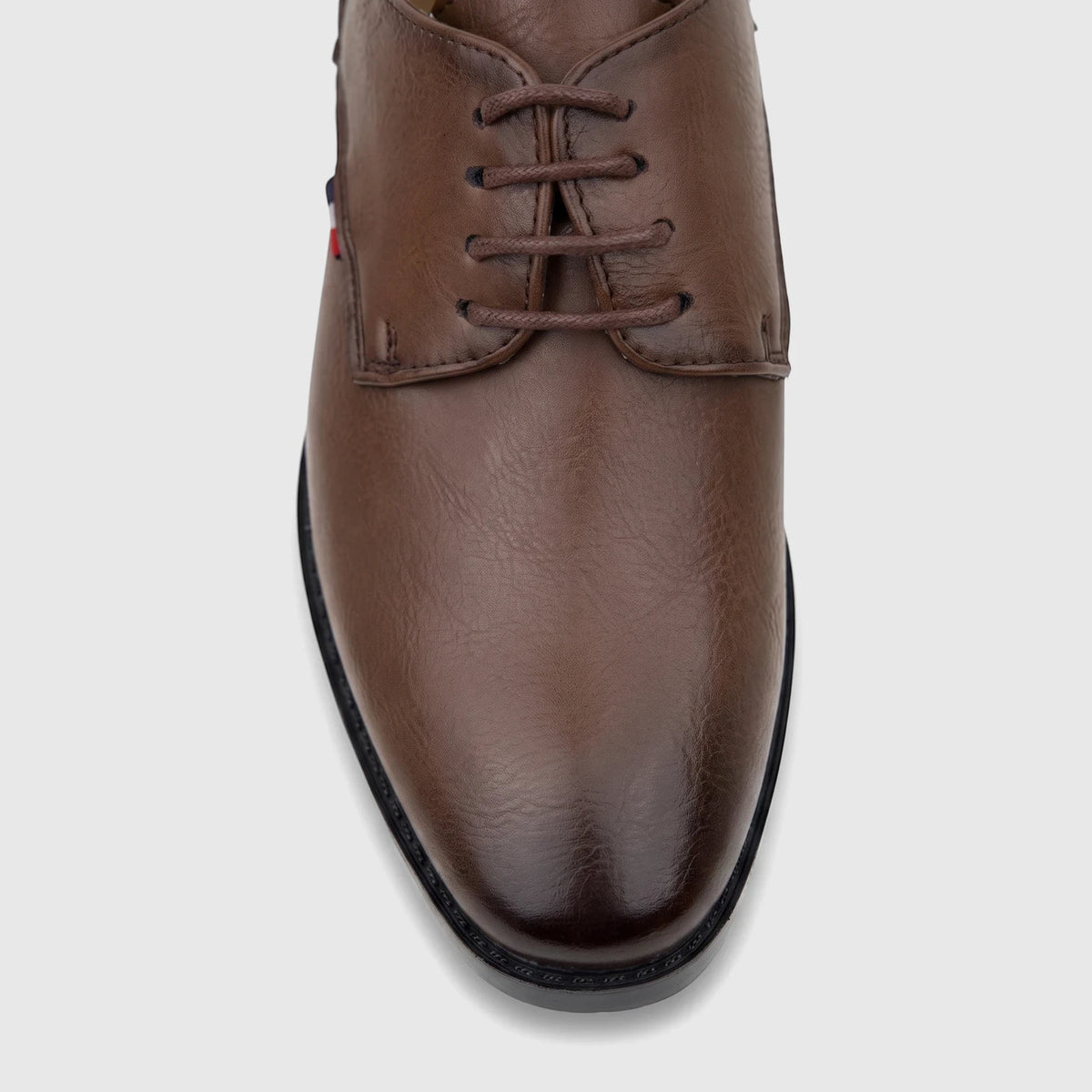 Brown leather lace-up dress shoe for boys, with textured surface and visible stitching, showcased from a top-front