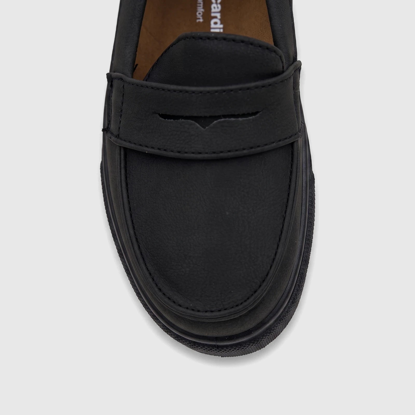 Close-up of a single black casual slip-on shoe for boys, featuring a penny loafer strap and a chunky ridged sole.