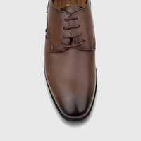 Brown boys youth dress shoe with laces, featuring a subtle red, white, and blue stripe detail on the side, viewed from above.