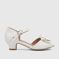 White girls' dress heel shoe with a bow, an ankle strap, and a low block heel, viewed from the side.