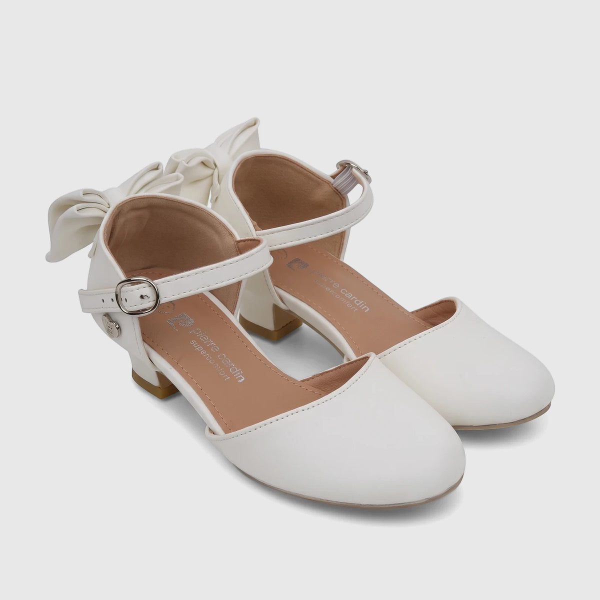 A pair of white PC Girls Dress Heels with elegant bows and ankle straps, featuring a comfortable low block heel.
