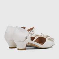 Pair of white PC Girls Dress Heels with an elegant bow and buckle, featuring a small heel, shown from a side perspective.