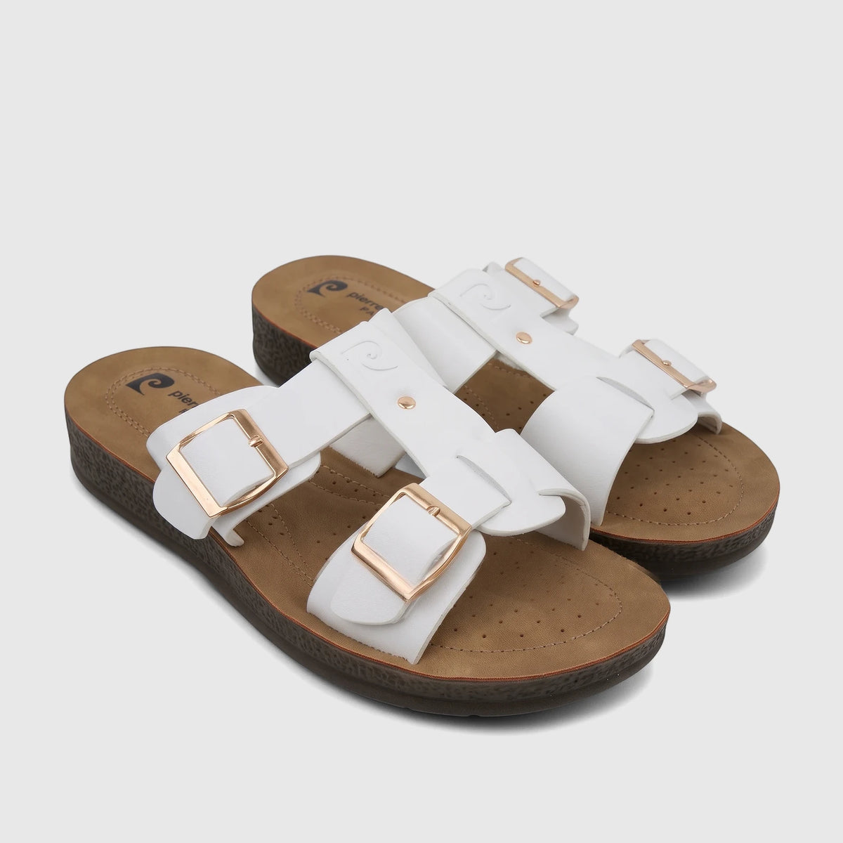 Pair of white Pierre Cardin ladies' casual sandals with gold buckles and brown perforated footbeds, displayed on a white