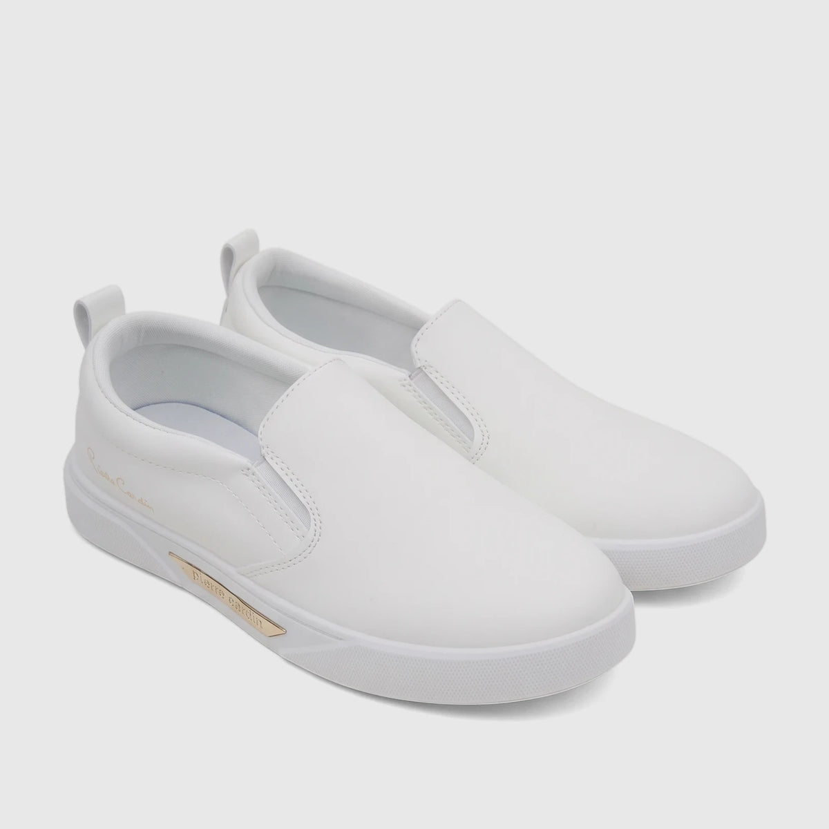 A pair of white PC Ladies Casual Slip On Sneakers, featuring gold branding details, displayed in a slightly elevated side