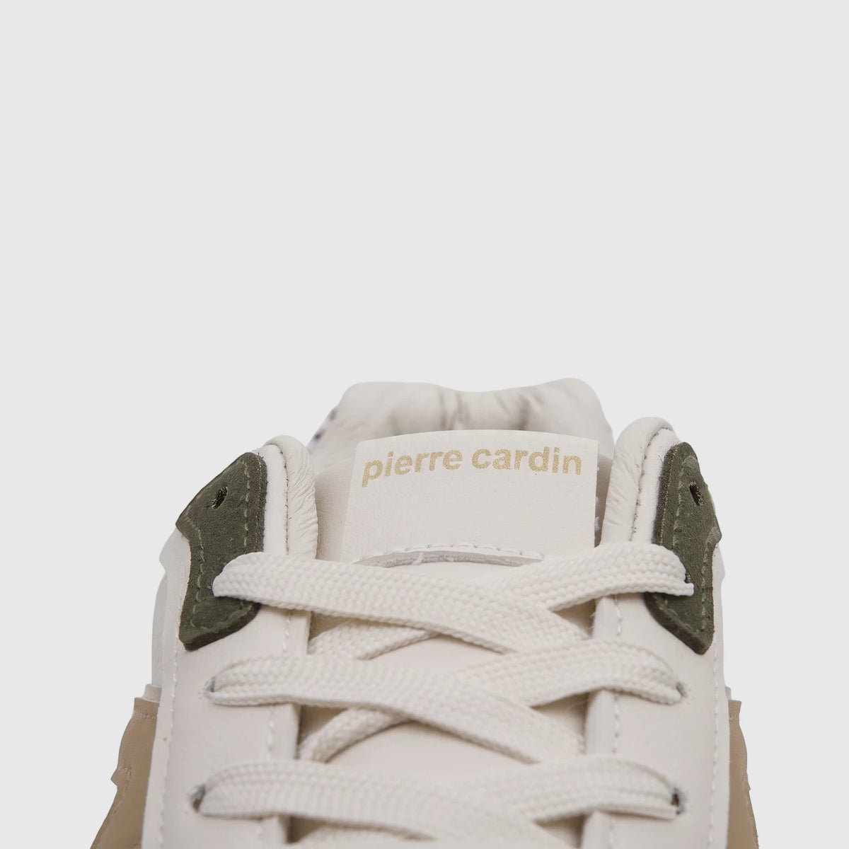 Close-up of a beige and olive Pierre Cardin ladies' casual sneaker showing laces and the brand logo on the tongue.