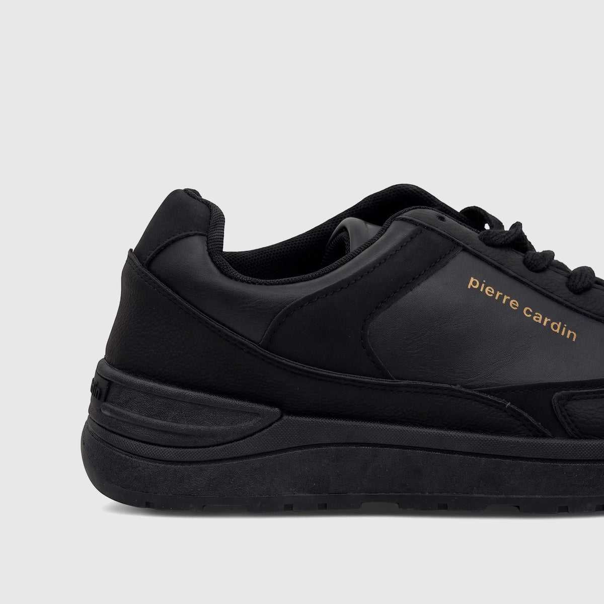 Close-up side view of a black Pierre Cardin Ladies Casual Sneaker PCL10987, featuring gold branding and leather-like texture.