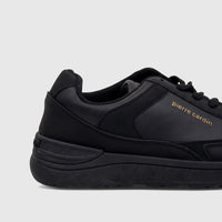 Close-up side view of a black Pierre Cardin Ladies Casual Sneaker PCL10987, featuring gold branding and leather-like texture.