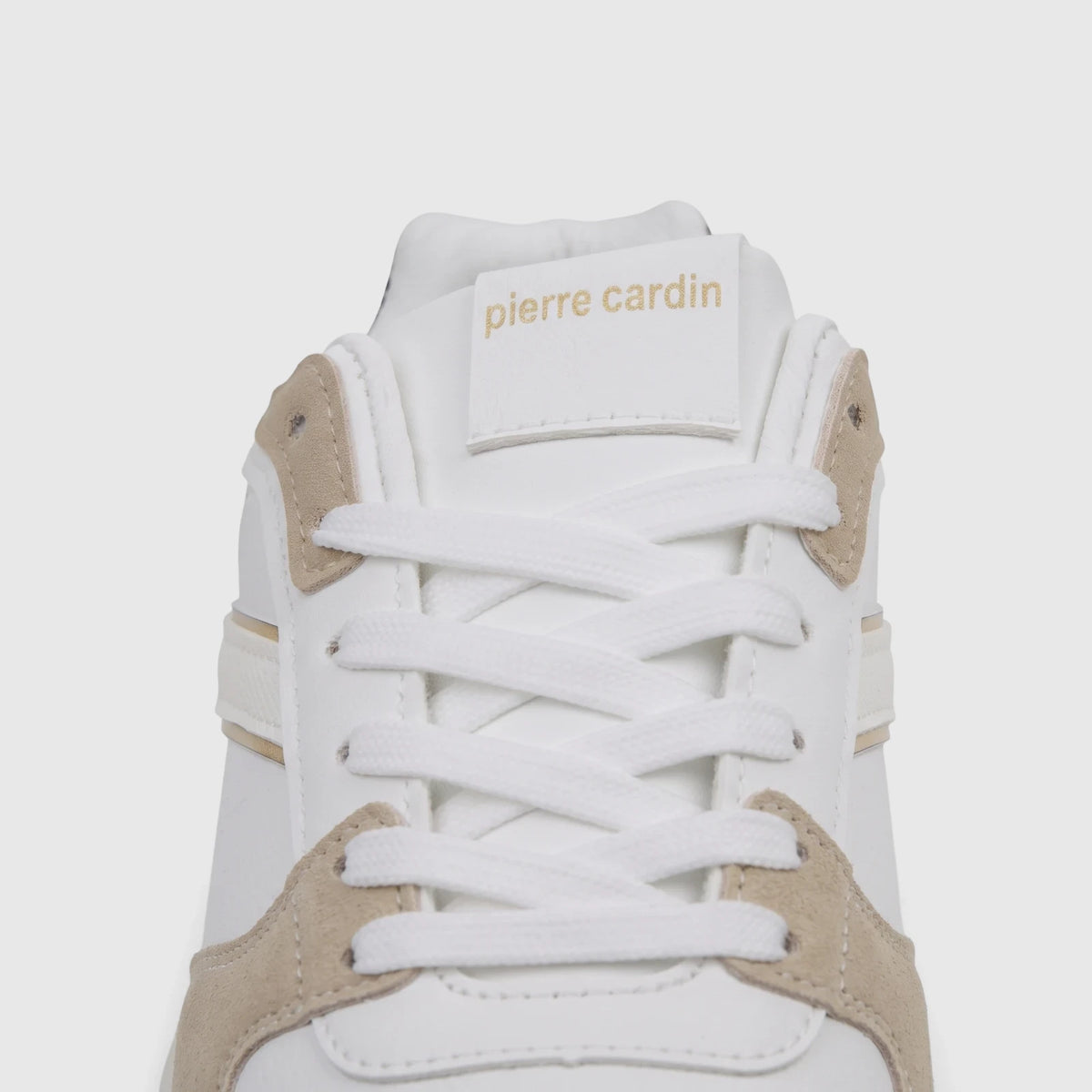 Close-up of a white Pierre Cardin ladies casual sneaker with white laces and beige accents on the tongue, showing the brand