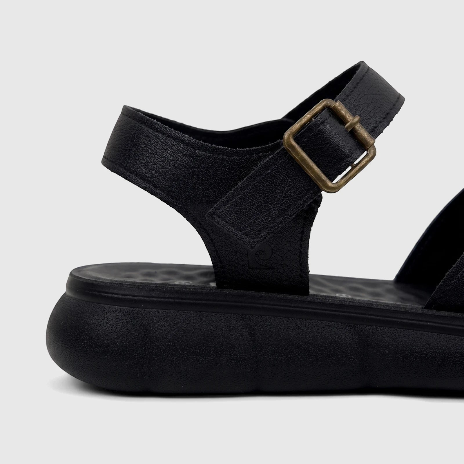Close-up of a black PC Ladies Comfort Sandal with a platform sole and a bronze buckle on the ankle strap.