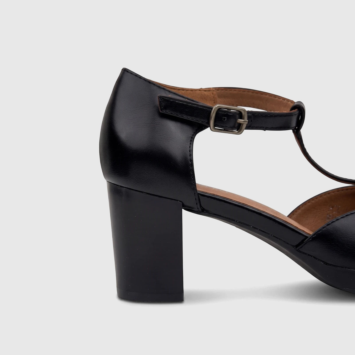 Close-up of a PC Ladies Dress black block heel T-bar shoe with an ankle strap and silver buckle, made from smooth material.