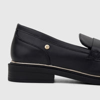 Black leather PC Ladies Dress Loafer with a gold emblem and silver trim, shown from a side view.