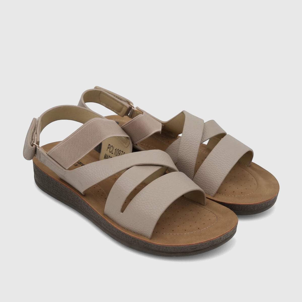 Pair of PC Ladies Nude Comfort Sandals with criss-cross straps, elasticated back, and a textured sole, resting on a white