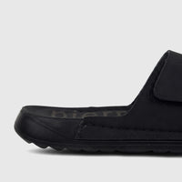 Close-up of a black PC Men's Casual/Comfort Sandal PCM00815 PM7 with a textured sole and velcro strap, viewed from the side.