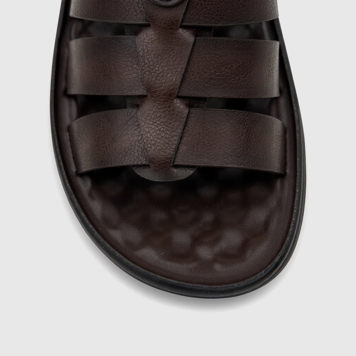 Close-up of a dark brown men's casual sandal with interwoven straps and a textured sole.