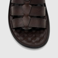 Close-up of a dark brown men's casual sandal with interwoven straps and a textured sole.