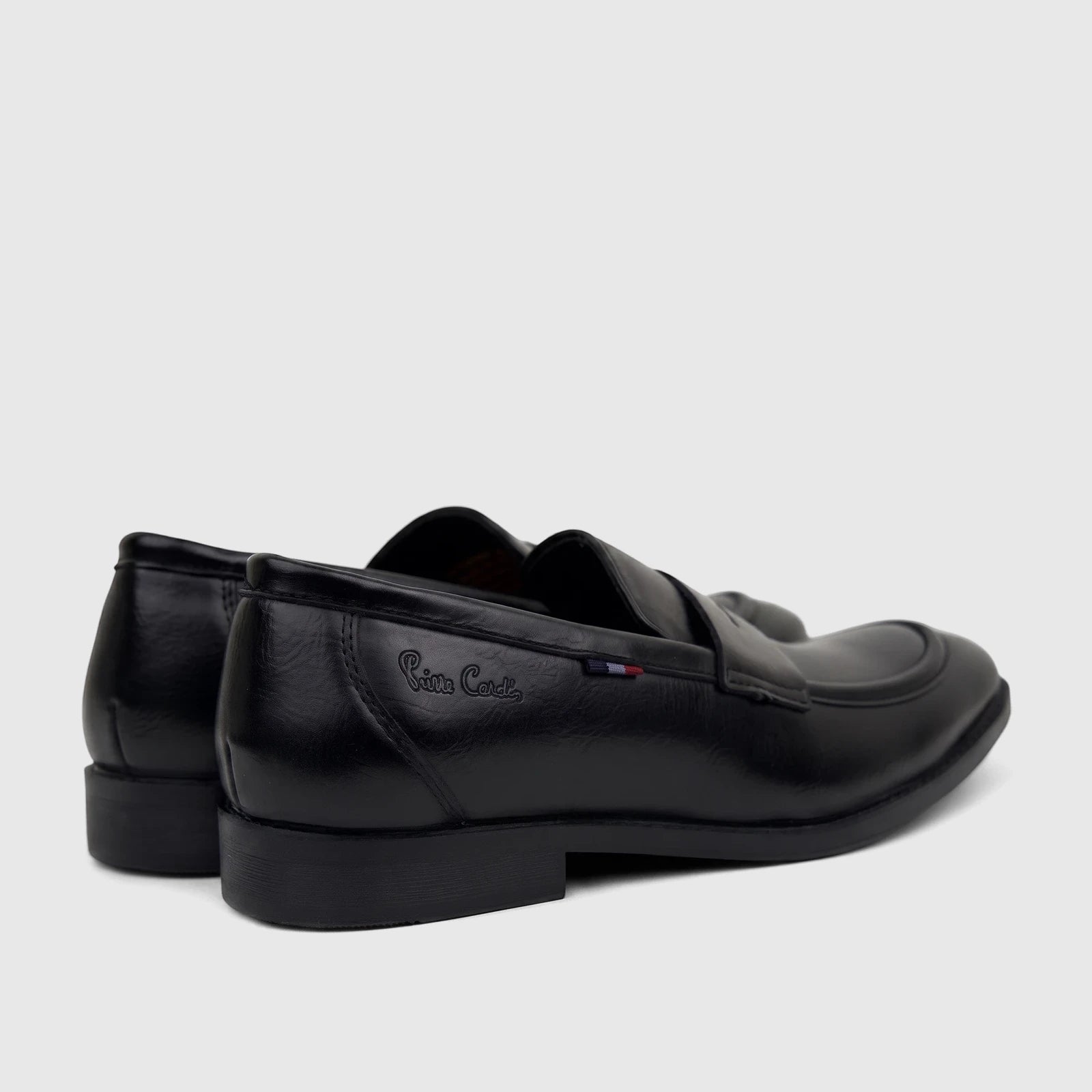 Black Pierre Cardin Boys Youth dress slip-on shoes, seen from a rear-side angle, showcasing the brand logo on the side.