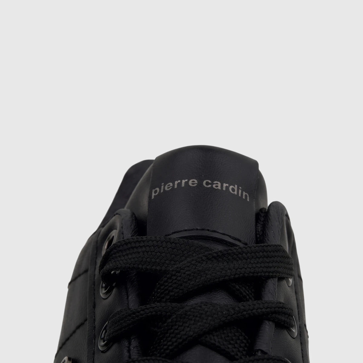 Close-up view of a black Pierre Cardin casual sneaker (PCL11006) showing the laces and the brand logo on the tongue.