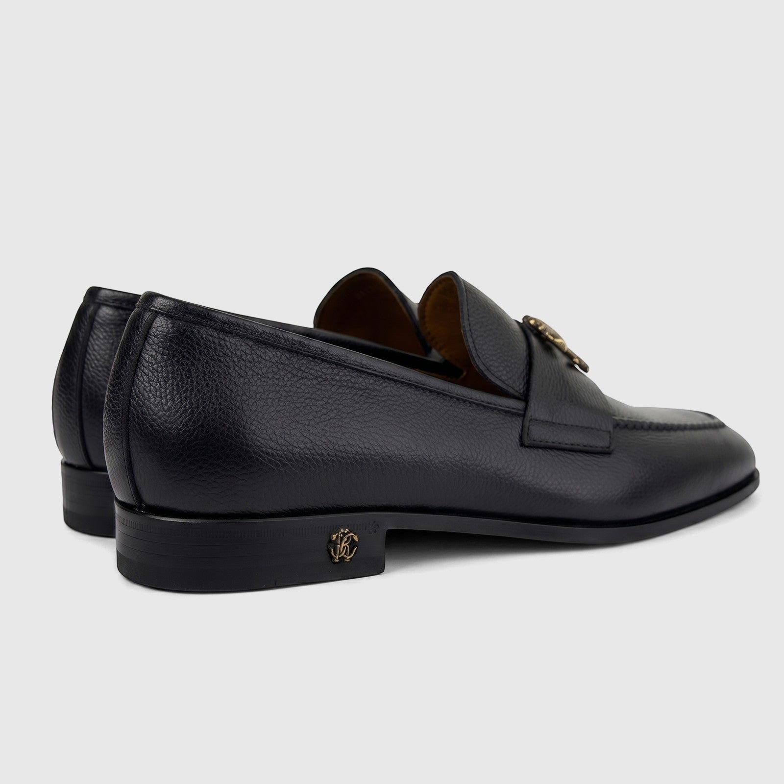 Roberto Cavalli men's black pebbled leather dress slip-on shoes with gold-tone logo details, viewed from the side.