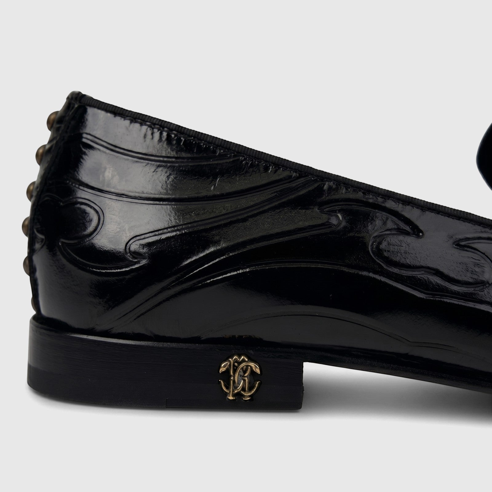 Roberto Cavalli men's black patent leather dress loafer with gold RC logo and studded heel, side view.