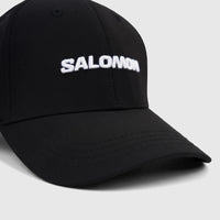 Close-up of a deep black Salomon adjustable cap with a white embroidered Salomon logo on the front, viewed from an angle.