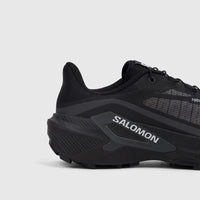 Close-up side view of a black Salomon Men's Genesis 2 trail running sneaker, highlighting its durable sole and activeCHASSIS.