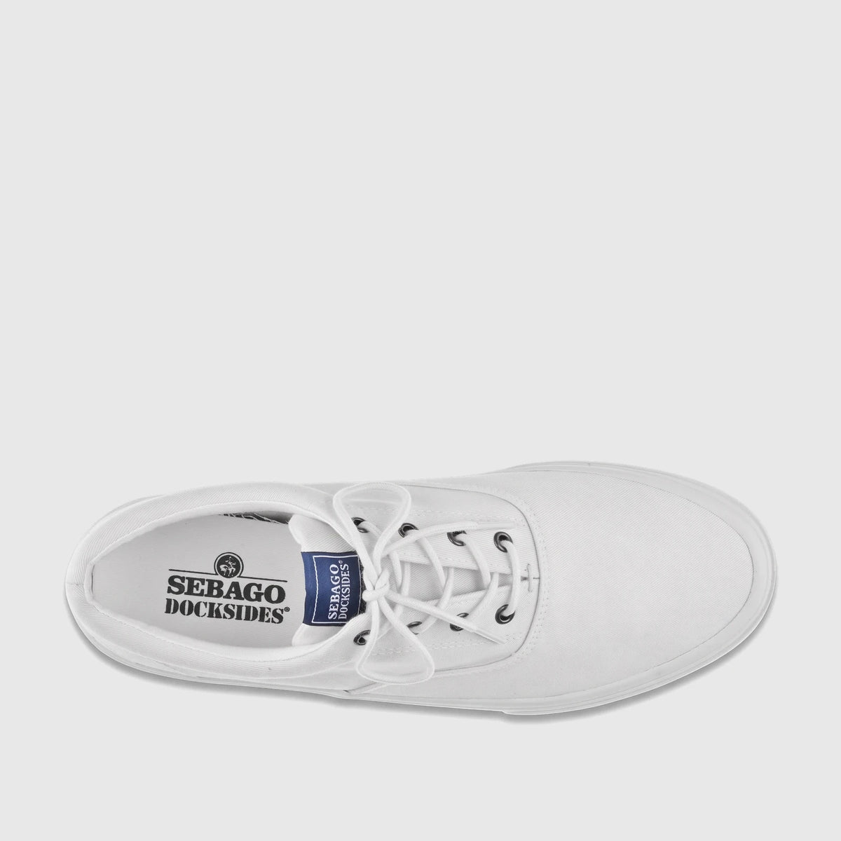 Top-down view of a white canvas Sebago Docksides men's sneaker, featuring white laces, black eyelets, and brand logos on the