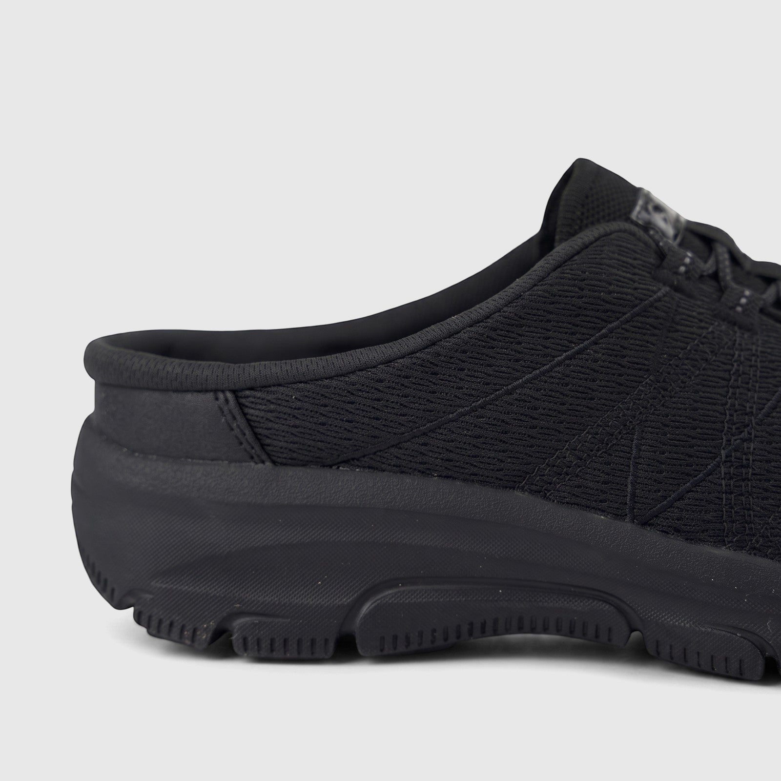 Skechers Ladies Comfort Open Back Easy Going black sneaker, showing the side profile of the heel and midfoot with mesh upper
